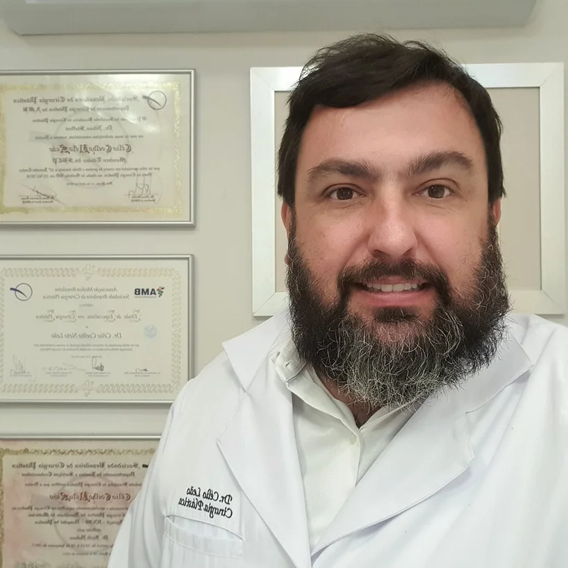 Dr. Celio Leao em consultorio, usando jaleco, com certificados ao fundo